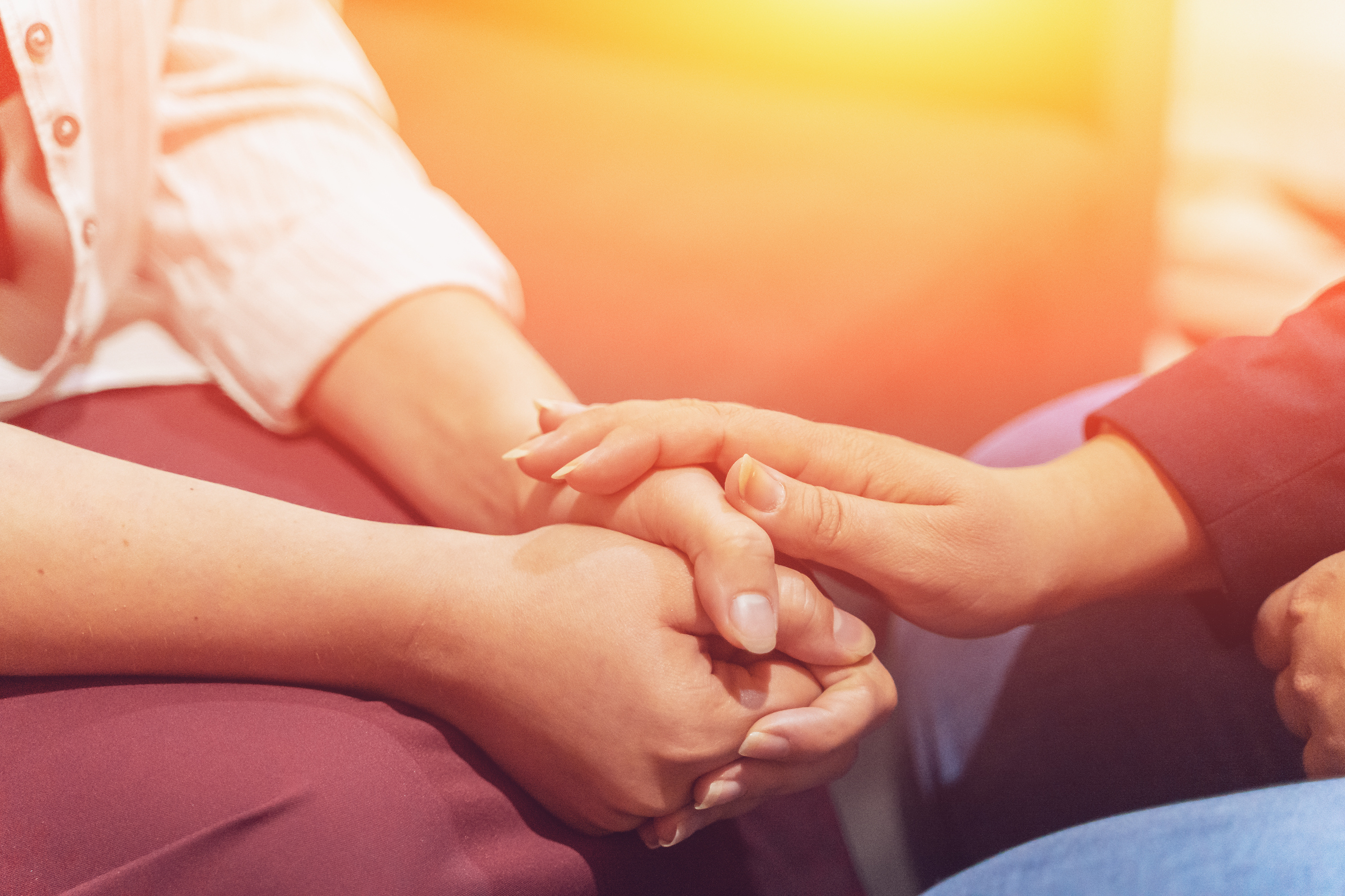 Eine Person legt die Hand auf die gefalteten Hände dre anderen.