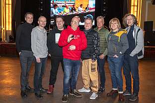 Gruppenfoto Dr. Stefan Moritz mit der Band Die Prinzen. Dr. Moritz hält den Tracer in die Kamera. Sie stehen im Saal des Steintor-Varietés.