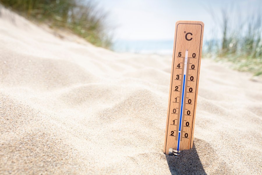 Ein Thermometer steckt im Sand und zeigt 35°C an. Im Hintergrund befinden sich Gräser und das Meer. Der Fokus liegt auf dem Thermometer, der Hintergrund ist unscharf.    Ein Thermometer steckt im Sand und zeigt 35°C an. Im Hintergrund befinden sich Gräser und das Meer. Der Fokus liegt auf dem Thermometer, der Hintergrund ist unscharf.  
