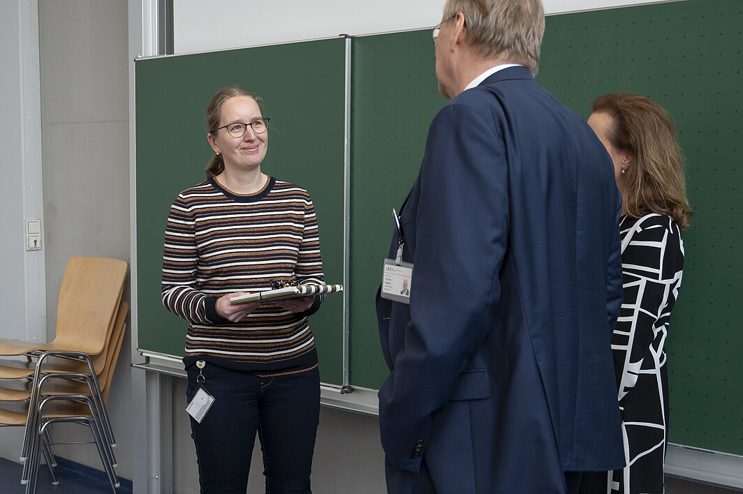 Jessica Höll lächelt in Richtung des Ärztlichen Direktors und der Dekanin, die ein Geschenk überreicht haben. 