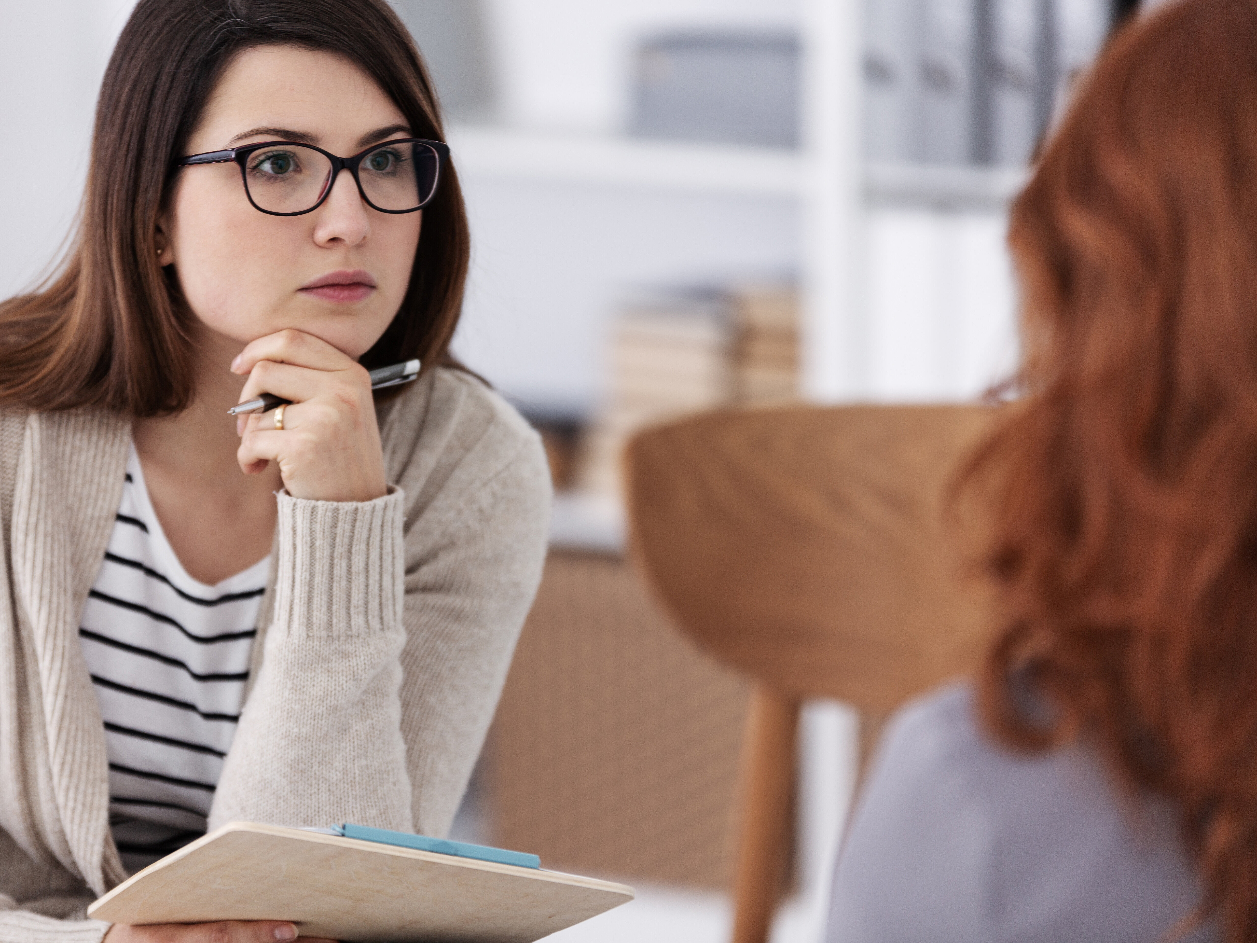 Zwei Frauen sitzen sich gegenüber am Tisch in einer Beratungssituation