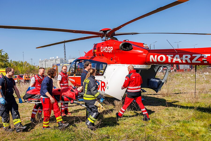 Rettungsteams transportieren eine verletzte Person auf einer Trage zu einem Rettungshubschrauber. Rettungsteams transportieren eine verletzte Person auf einer Trage zu einem Rettungshubschrauber.
